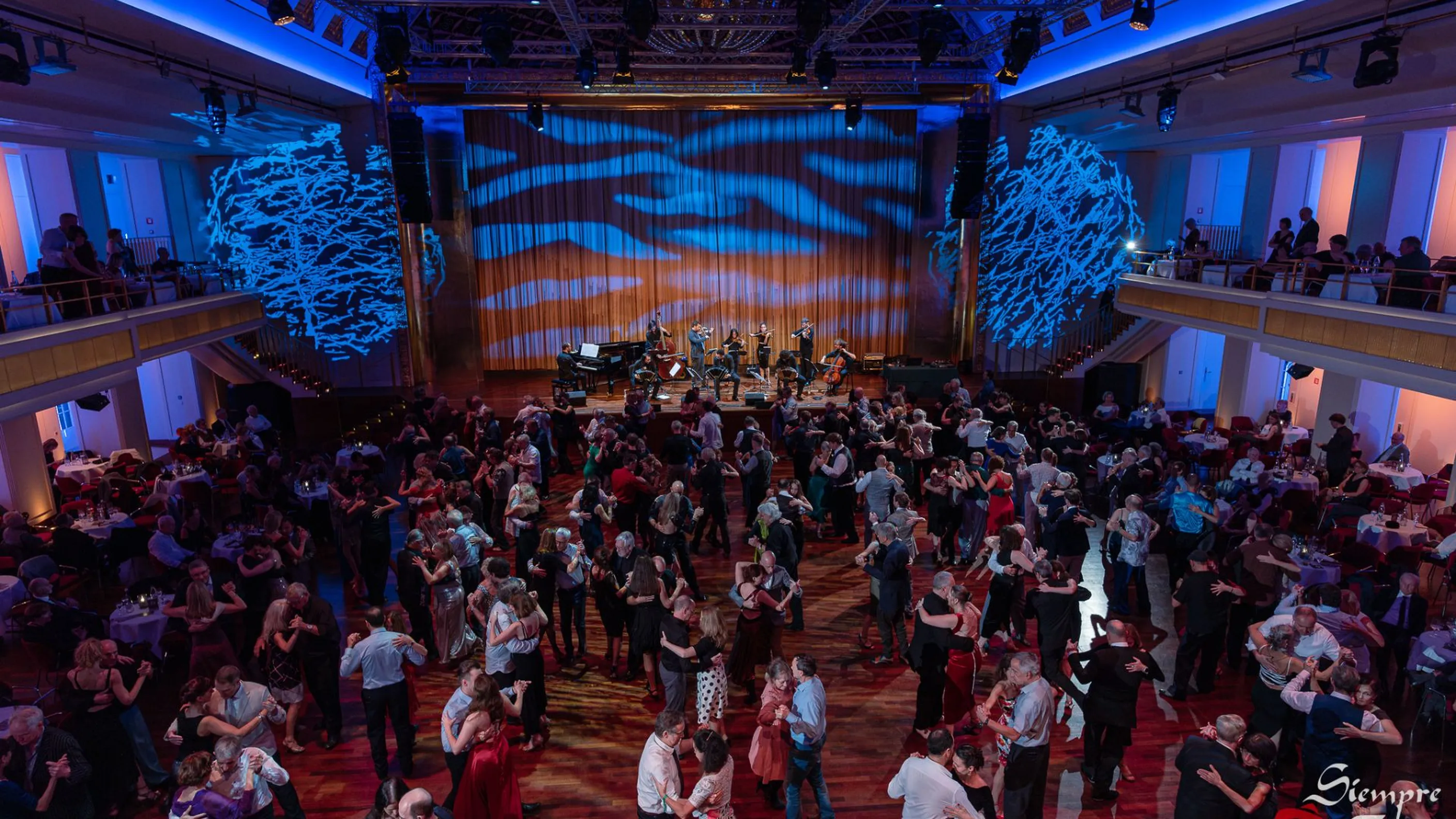 Zahlreiche Paare tanzen Tango im Bénazetsaal des Kurhauses Baden-Baden, während ein Ensemble live auf der Bühne spielt